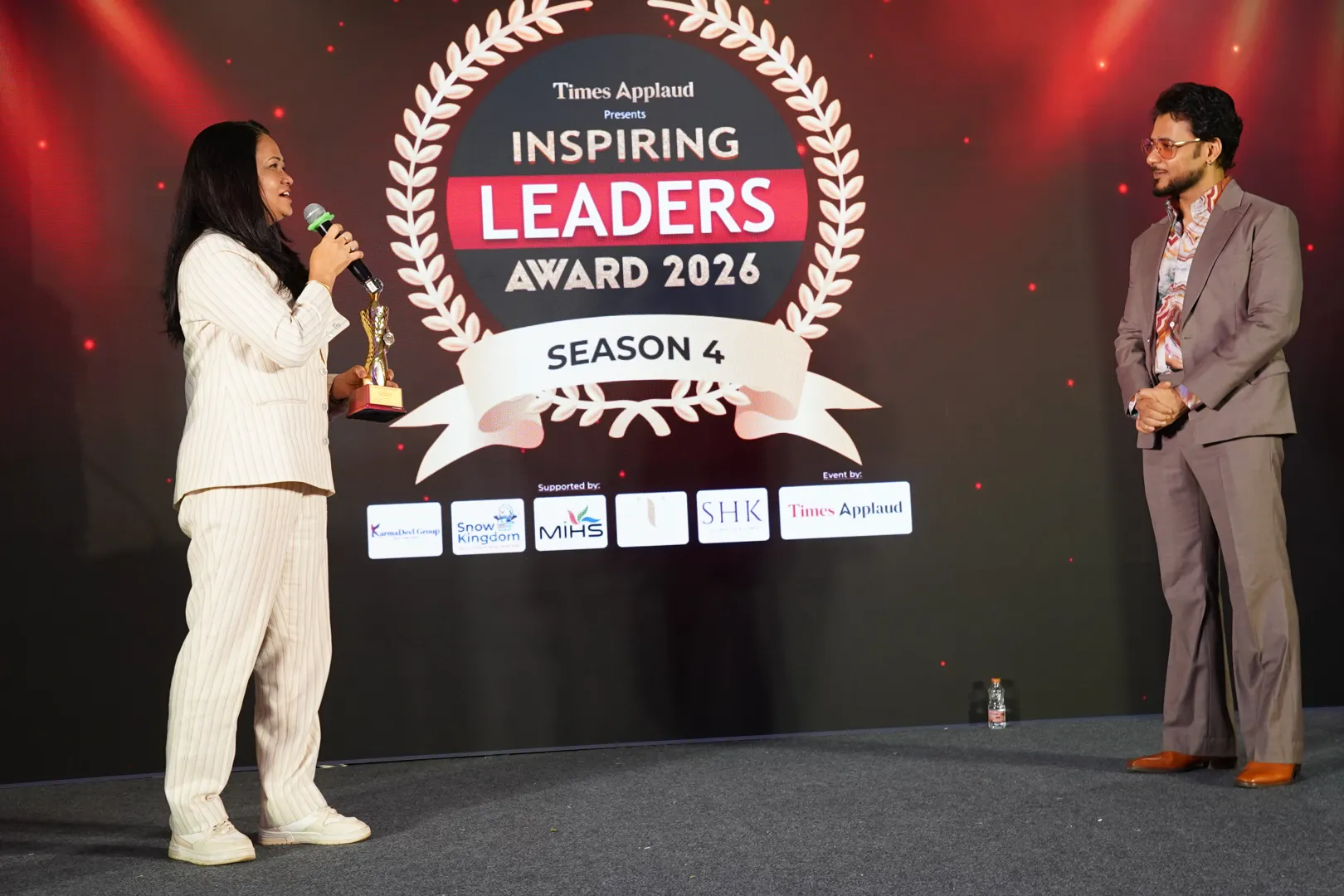 Dr. Reshma Jain on stage holding a trophy at the Inspiring Leaders Award 2026